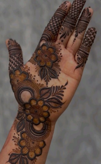 A delicate, intricately patterned henna design adorns the elegant, outstretched hand of a regal figure. The intricate floral motifs and swirling vines, rendered in a rich, warm palette, cascade across the fingers and palm, exuding a sense of refined sophistication. Soft, diffused lighting casts a gentle glow, accentuating the subtle textures and contours of the mehndi art. The hand is positioned in a graceful, poised gesture, conveying a sense of poise and regality. The background is a serene, neutral tone, allowing the mesmerizing mehndi design to take center stage and captivate the viewer.